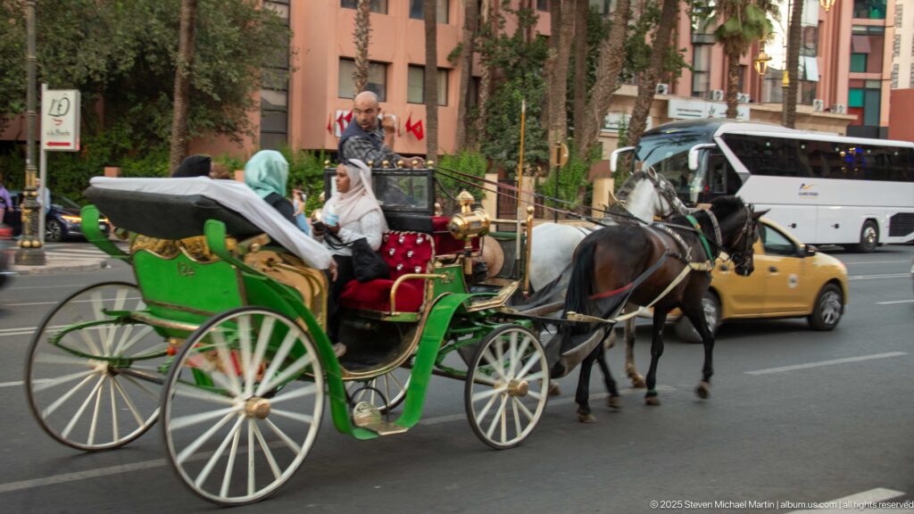 Green horse-drawn calèche with passengers moving through Marrakech traffic beside taxis and a bus.