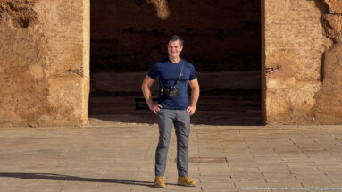 Visitor standing in a broad doorway framed by thick earthen walls inside the ruins of Badii Palace.