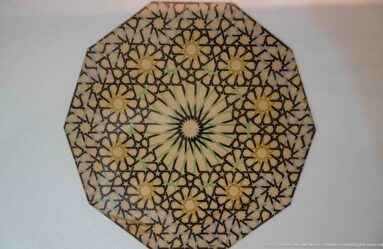 Octagonal display of a reconstructed zellij design with a central green-white star and surrounding ochre rosettes.