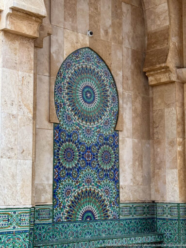 Colorful geometric zellij tile panel set in an arched recess above a matching tiled dado near the Badii Palace entrance.