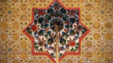 Star-shaped Bahia Palace ceiling medallion containing a stylized multicolored bouquet against a gold patterned field.