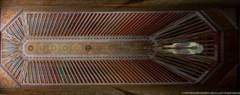 Long painted timber ceiling with red and green beams, intricate central ornament and a hanging lantern.