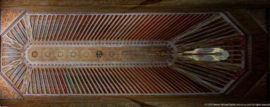 Long painted timber ceiling with red and green beams, intricate central ornament and a hanging lantern.