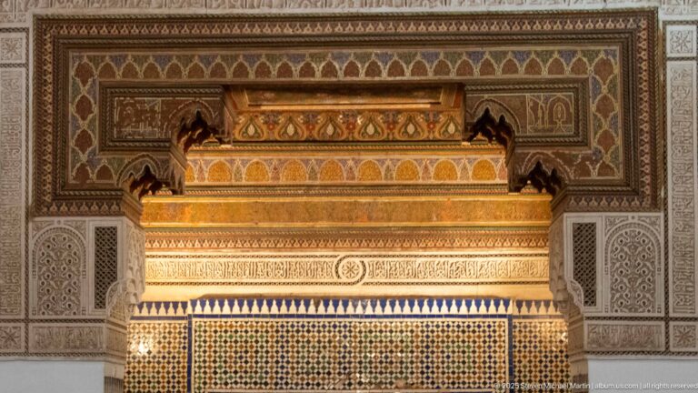 Close view of Bahia Palace fireplace hood with carved bands, painted ornament, geometric tilework and pale side panels.
