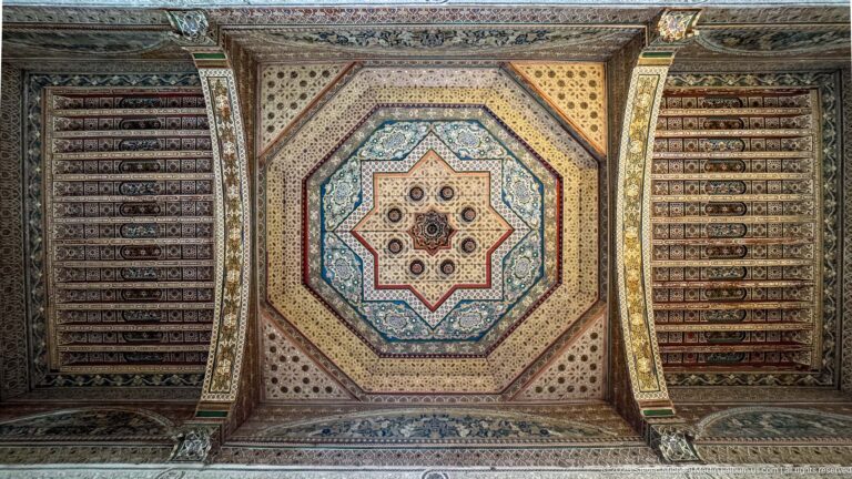 Octagonal painted Bahia Palace ceiling with central star motif, layered geometric borders and flanking decorated beams.