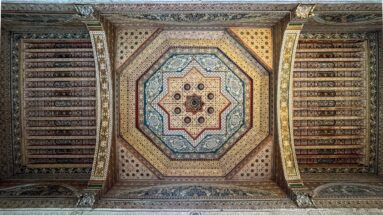 Octagonal painted Bahia Palace ceiling with central star motif, layered geometric borders and flanking decorated beams.