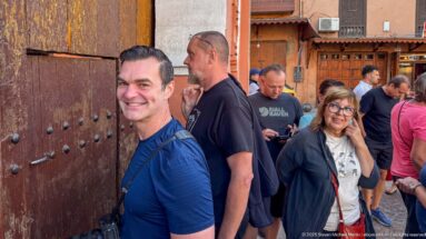 Visitors gathered beside the large studded wooden entrance doors of Bahia Palace in Marrakech.