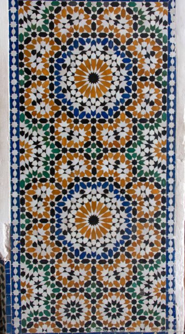 Square Bahia Palace zellij panel with interlocking blue, green, ochre, black and white geometric patterns.