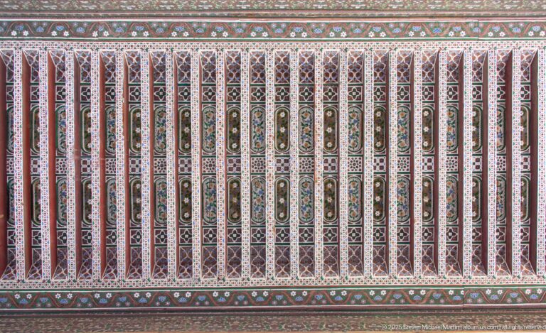 Long Bahia Palace painted timber ceiling with red ribs and repeating green, cream and geometric panels.