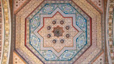 Octagonal Bahia Palace ceiling with a large central star, nested painted borders and multicolored floral-geometric motifs.