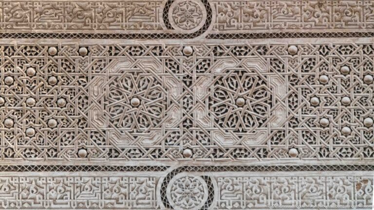 Close carved plaster panel with interlaced geometry, star forms and circular rosette medallions at Bahia Palace.