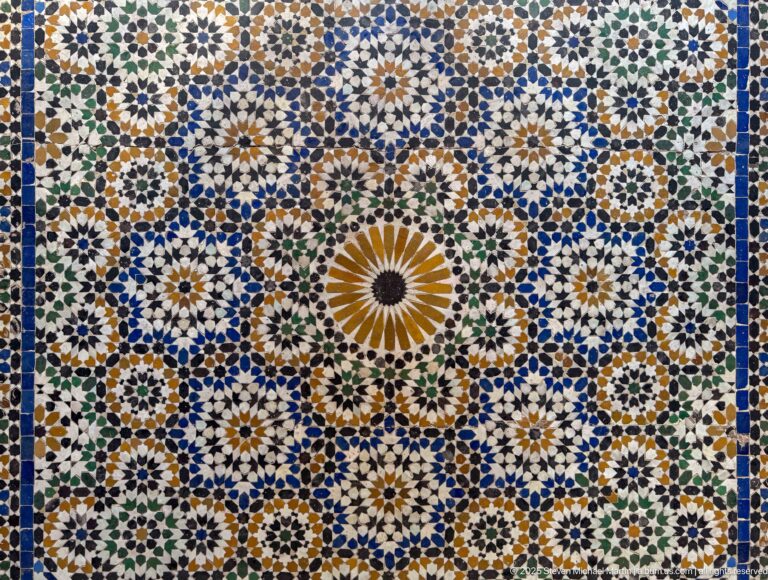 Large Bahia Palace zellij panel with central ochre rosette and dense blue, green, white and ochre star patterns.