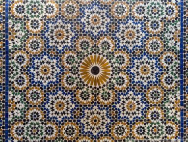Large Bahia Palace zellij panel with central ochre rosette and dense blue, green, white and ochre star patterns.