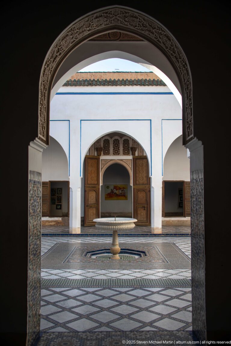 Bahia Palace courtyard fountain and far doorway framed by a dark carved interior arch.