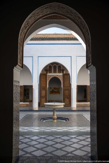Bahia Palace courtyard fountain and far doorway framed by a dark carved interior arch.