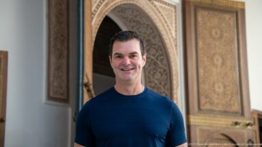 Close visitor portrait at Bahia Palace framed by carved archwork and painted wooden door panels.