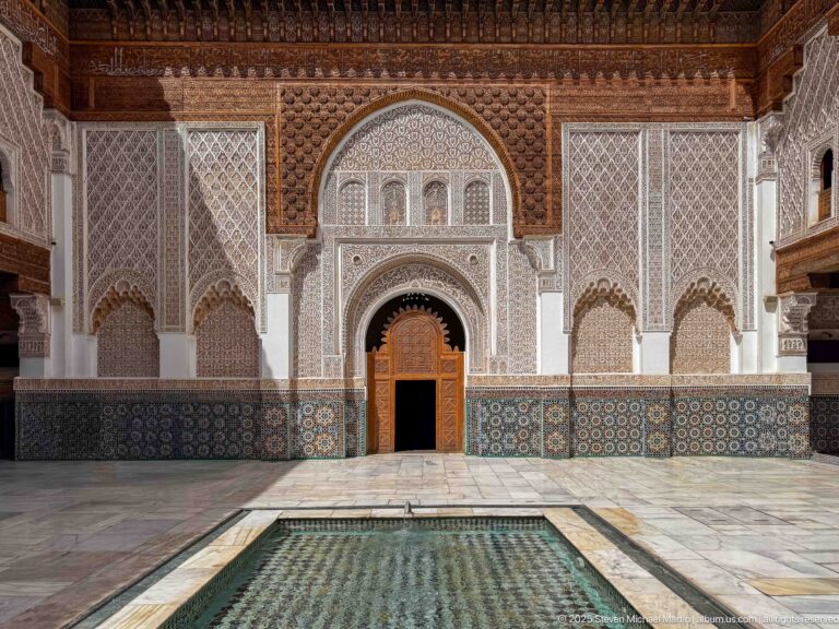 Symmetrical view across the central courtyard pool toward the ornate arched façade, without visitors in the main axis.