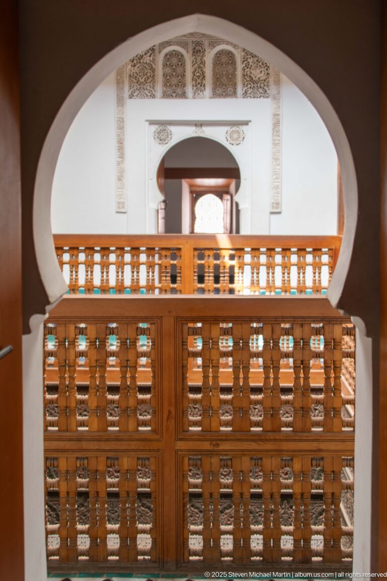 Broad oval arch framing wooden gallery rails and a second decorated doorway in the distance.