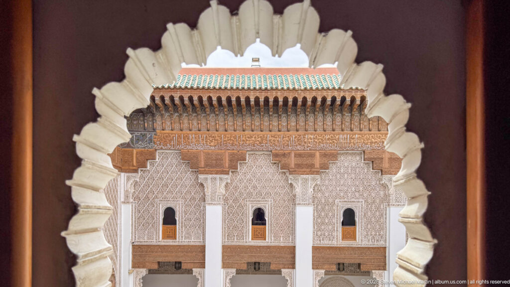 Tightly framed symmetrical courtyard gallery with three bays, carved plaster, timber eaves, and green roof tiles.