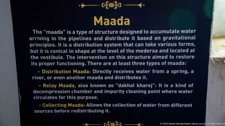 Interpretive sign titled “Maada” describing gravity-fed water distribution, relay, and collecting structures at the madrassa.