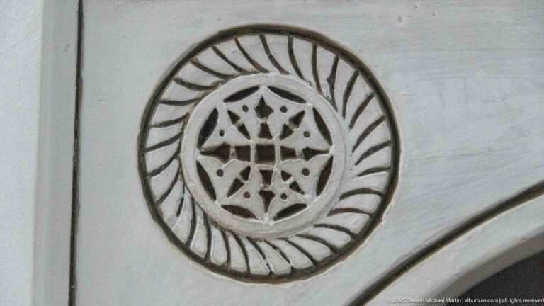 Close view of a circular carved stucco medallion with an interlaced star center and radiating border motifs.