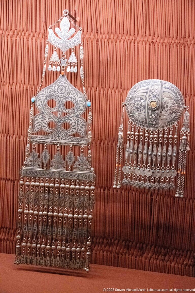 Two silver-colored ornaments with decorated upper plates and dense rows of hanging metal pendants.