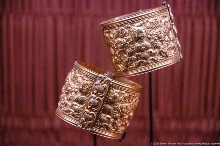 Two wide metal cuff bracelets with raised figurative and floral repoussé decoration and beaded borders.