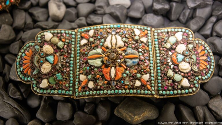 Three-part metal clasp densely decorated with turquoise-colored beads, shells, orange coral, and multicolored stones.