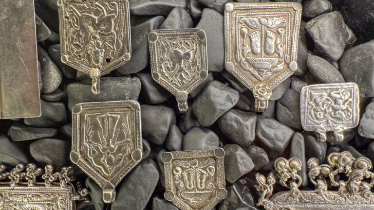 Silver-toned shield- and hand-shaped pendants with raised or engraved Arabic calligraphy.