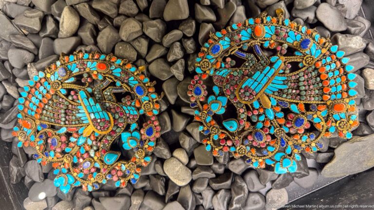 Pair of round ornaments with turquoise and orange-red stones centered on stylized hand motifs.