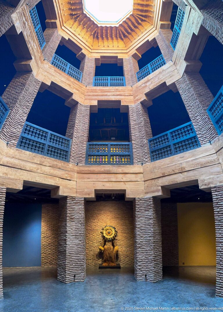 Lower level of MAP Marrakech’s octagonal light well with brick piers, deep display bays, timber galleries, and screened upper windows.