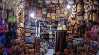 Compact souk shop with walls and ceiling densely hung with leather bags, pouches, wallets, and decorated satchels.