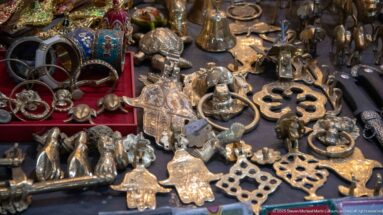 Tabletop crowded with small cast-metal hands, animal figures, door knockers, rings, and decorative ornaments.