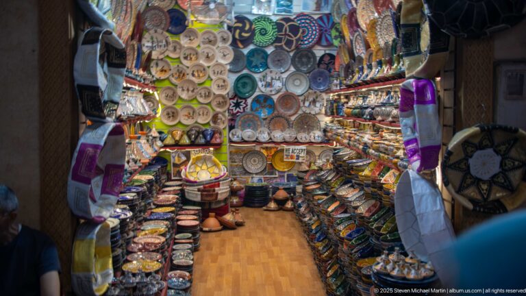 Small shop packed with painted ceramic plates, tagines, bowls, lamps, and decorative crafts.