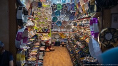 Small shop packed with painted ceramic plates, tagines, bowls, lamps, and decorative crafts.