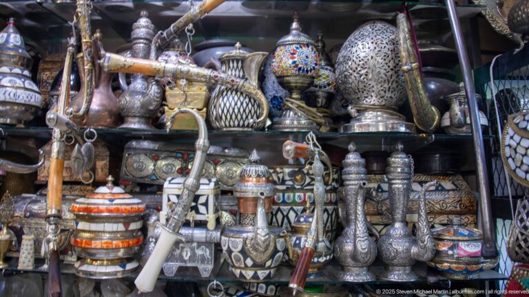 Engraved and pierced metal pitchers, vases, lanterns, and decorative vessels crowded on shop shelves.