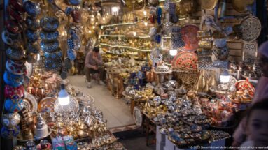 Narrow shop glowing with lamps and packed with trays, teapots, bowls, and decorative metalware.