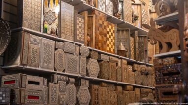 Shelves filled with carved and inlaid wooden boxes decorated with geometric patterns.
