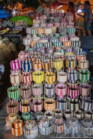 Stacks of rolled striped woven bands in bright multicolored patterns.