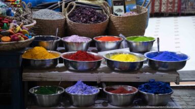 Metal bowls filled with vivid colored powders in blue, green, red, yellow, purple, and pink.