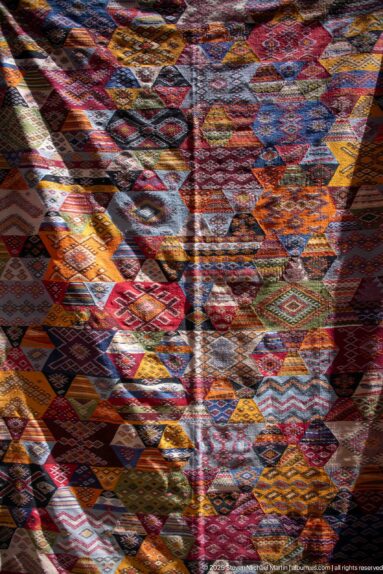 Close view of multicolored woven textiles with diamonds, zigzags, stripes, and geometric motifs.