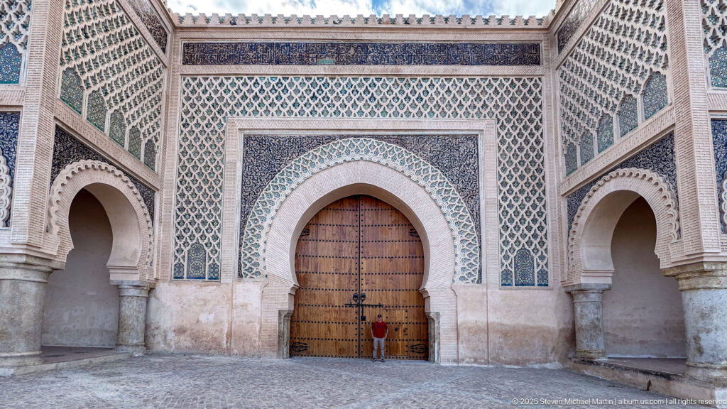 Symmetrical decorated gateway with closed central doors and open arches on both sides.