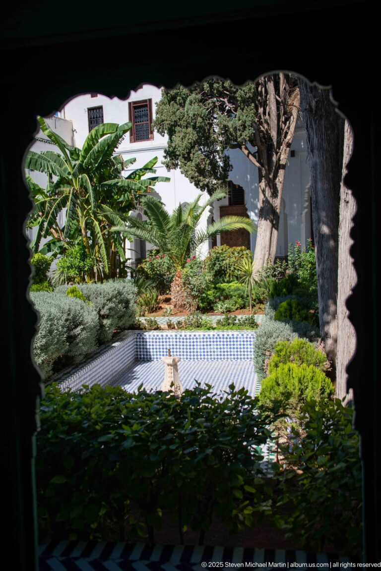 Shaded courtyard garden with dense foliage surrounding a small blue-and-white tiled fountain or basin.