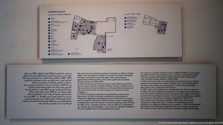 Wall display with a floor plan of Dar Jamaï above multilingual historical interpretation panels.