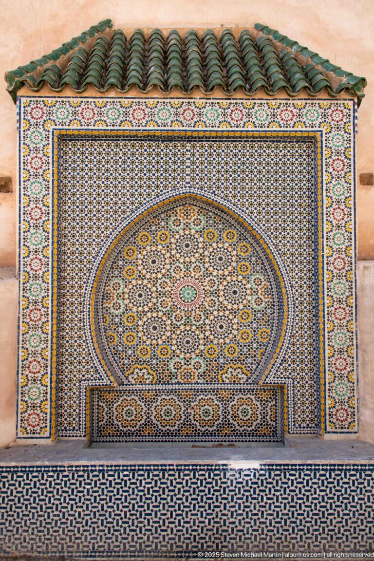 Frontal view of a zellij fountain panel centered on a large circular multicolored rosette.