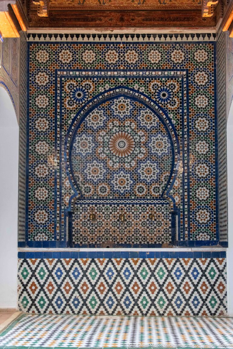 Large arched zellij fountain with central radial medallion, diamond-pattern base, and tiled floor.