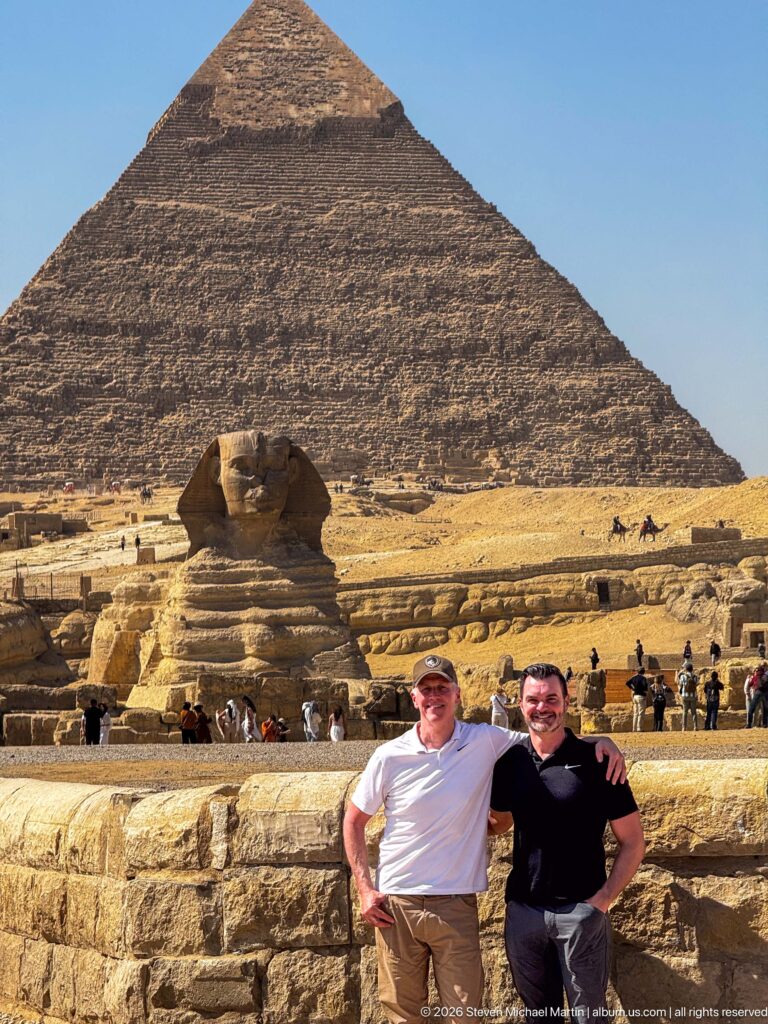 Two men posing together before the Great Sphinx and the Pyramid of Khafre on the Giza Plateau.
