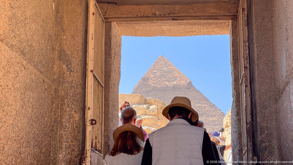 Pyramid centered through a rectangular ancient stone doorway with visitors standing in the shaded passage.