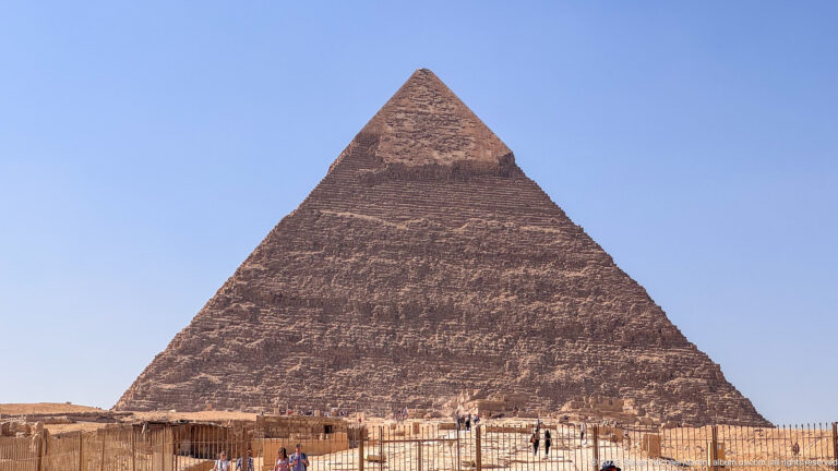 Near-frontal view of the Great Pyramid of Khufu with visitors and fencing along its base.