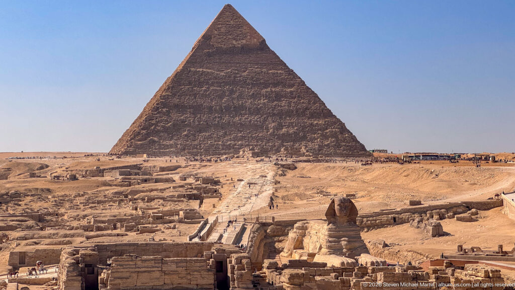Elevated view of the Great Sphinx, its enclosure and approach, with a major Giza pyramid behind.